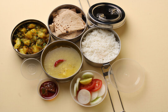 Typical Stainless steel Lunch Box or Tiffin with Maharashtrian food menu Chapati OR Roti, Plain Dal Tadka, White Rice Potato sabji with salad and pickle
