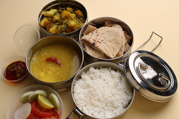 Typical Stainless steel Lunch Box or Tiffin with Maharashtrian food menu Chapati OR Roti, Plain Dal Tadka, White Rice Potato sabji with salad and pickle