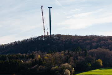 Country landscape with crane at wind turbine