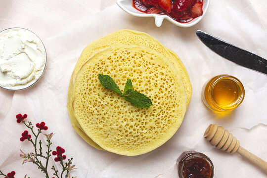 Homemade traditional moroccan baghrir with honey, strawberries and mint from above