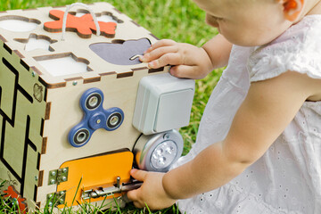 Cute girl inserts figures into recesses on development board. Toys for development of fine motor...