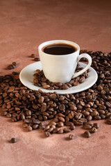 White coffee cup and beans on brown bckground