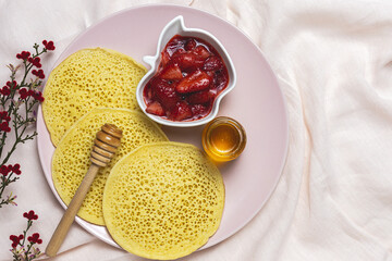 Homemade traditional moroccan baghrir with honey, strawberries and mint from above