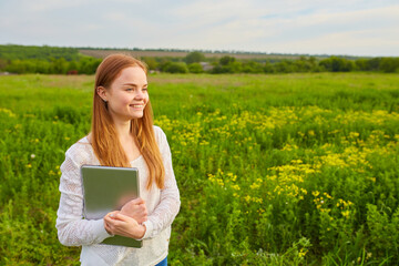 girl working in nature with a laptop lying on the green grass. The girl works as a freelance traveler.