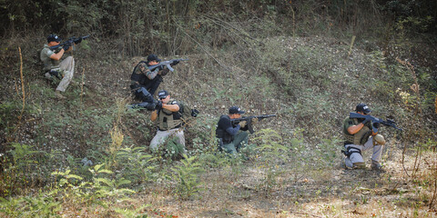 Army soldiers shooting with rifle machine gun in the forest. Nature outdoor military combat training