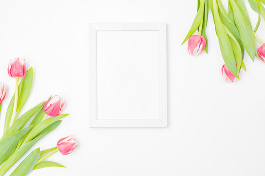 Mockup with a white frame and pink tulips on white background