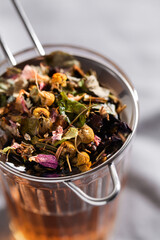 Herbal tea with chamomile, rose and mint on gray background close-up. Home remedy concept
