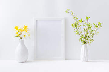 Home interior with easter decor. Mockup with a white frame and spring flowers in a vase on a light...