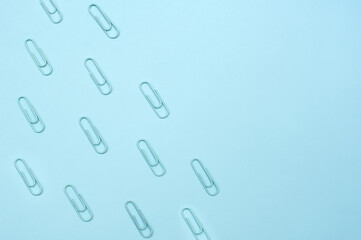 Blue paper clips on a blue background.