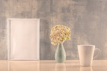 Modèle de cadre photo blanc avec espace vide pour logos, inscription publicitaire. Cadre en mode portrait sur un espace de travail avec une tasse. Ambiance zen.