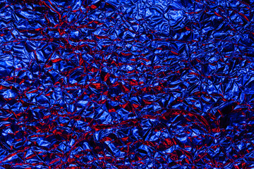 Blue foil background with shiny crumpled surface for texture background. Iridescent surface wrinkled foil
