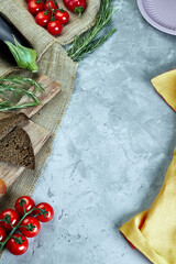 light gray concrete background with burlap bread tomatoes greens and eggplant
