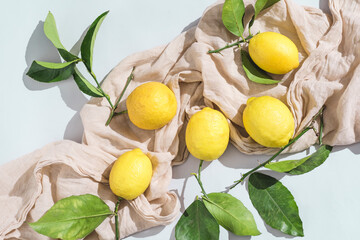 Ripe fresh Sicilian lemons with green leaves on on natural linen fabric. Organic citrus fruits with bright sunlight. Healthy food concept