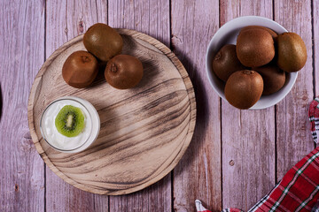 Yoghurt glass with kiwis on wooden plate