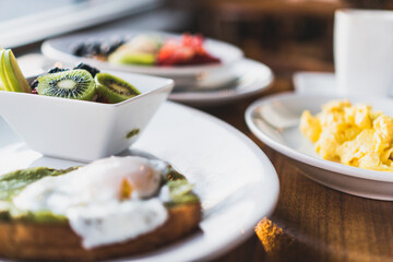 nutritious breakfast with scrambled eggs, fried egg on avocado toast, oatmeal with fruit as well as fresh fruit