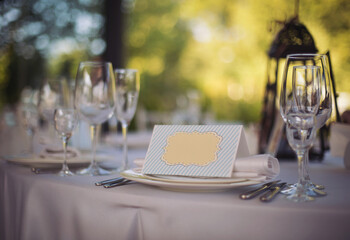 Festive tables at the wedding party, on the tables are plates with napkins and cards, glasses. elegant dinner table setting in restaurant or hotel.