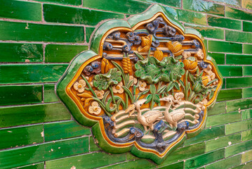 Beijing, China - April 27, 2010: Forbidden City. Closeup of flower and bird themed ceramics artwork on green wall.