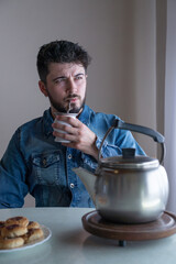 Young and handsome argentine or argentinian man drinking mate, in a warm environment.