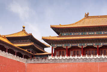 Naklejka premium Beijing, China - April 27, 2010: Forbidden City. Meridain Gate corner and other buildings seen over red wall under blue sky. Chinese architecture.
