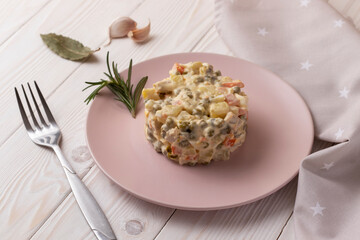 Olivier salad with vegetables, meat and mayonnaise. On a white wooden table.