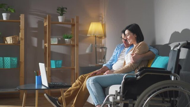a couple of spouses a young disabled woman in a wheelchair spend time together sitting on the couch close up