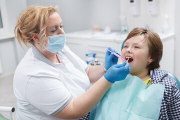 Professional dentist giving fluoride dental treatment to a young boy - obrazy, fototapety, plakaty