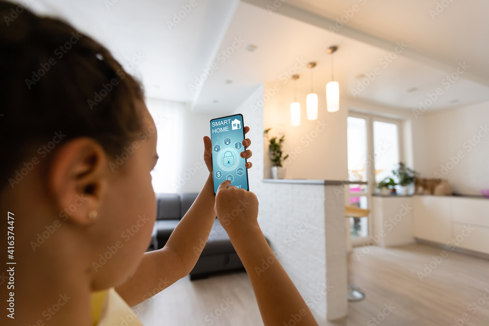 Poster shot of little girl using a domotic system with her digital tablet while standing at home.