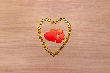 Hearts on wooden background with yellow sparkles. Valentine's Day or Mother's Day greeting card.