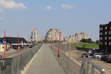 a road at the boulevard next to the harbour and marina in breskens, zeeland, the netherlands in summer with modern apartment buildings and hotels in the background