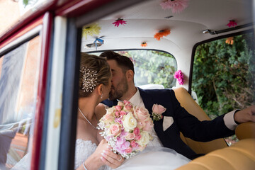 Das Brautpaar sitzt im Auto und küsst sich. Das Auto ist von ihnen geschmückt.