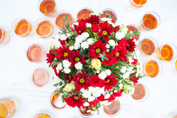 bouquet of flowers on a white sheet with glasses of wine