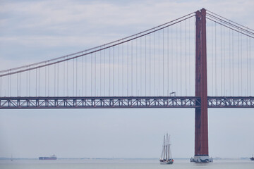 Dreimaster läuft unter der Tejo-Brücke nach Lissabon ein