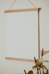 White frame on the wall with white paper and standing next to flower
