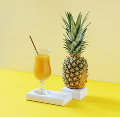 Pineapple fresh juice in glass on yellow background.