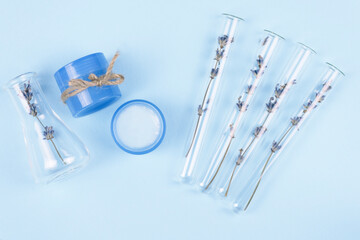 Test tubes and jars with natural cosmetics from lavender on a blue background. Lavender cream.