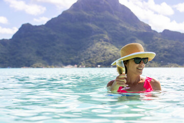 Woman drinking champagne in clear ocean water on the island of Bora Bora