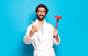 young bearded man wearing bathrobe with a plunger