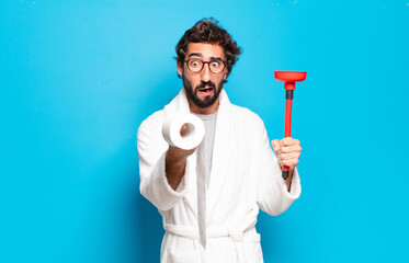 young bearded man wearing bathrobe with a plunger
