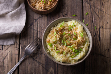 Traditional Irish dish colcannon, mashed potatoes with cabbage and green onions, on top of crispy fried cabbage topping with nuts and spices on a wooden table