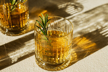Whiskey in a glass decorating with rosemary.the sun's rays pass through the glass