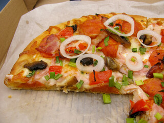 fresh pizza with mushrooms, pepperoni sausage and onion without one piece in a cardboard box