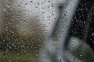Rain drops on window glasses surface with cloudy background . Natural Pattern of raindrops isolated on cloudy background. Traffic jam in rainy day with raindrops on car glasses. in bangkok.