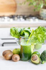 glass with green healthy smoothie, nutritious breakfast, vegetarian food, raw vegetables in the morning, broccoli, avocado, celery, salad, kiwi apple, lime. right food for the whole family, diet