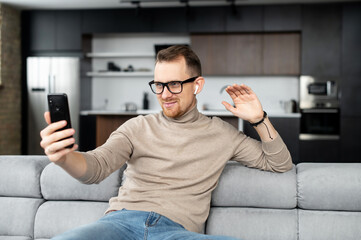 Video call concept, young good-looking, sincere man is using a phone for video connection, meeting...