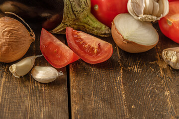 vegetables for the eggplant saute: eggplant, tomatoes, onions and garlic on a wooden table