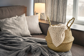 Straw wicker basket with knitting on sofa