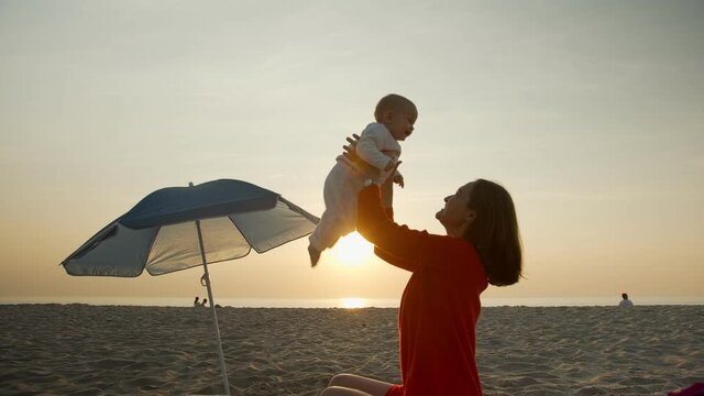 Happy mom with baby on sunset background