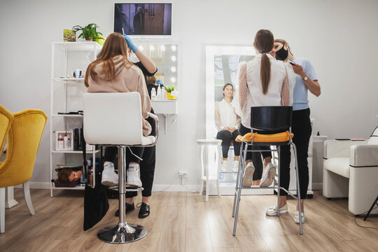 Makeup artists make up young women in beauty salon. Customer service in interior room to create an amazing image. Work make up creation wizard. Concept of style and measure satisfaction. Copy space