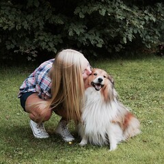 Photo of a young woman kissing her dog
