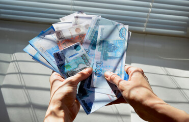 female hands hold an unfolded pile of Russian money, in the hands of bills of different denominations